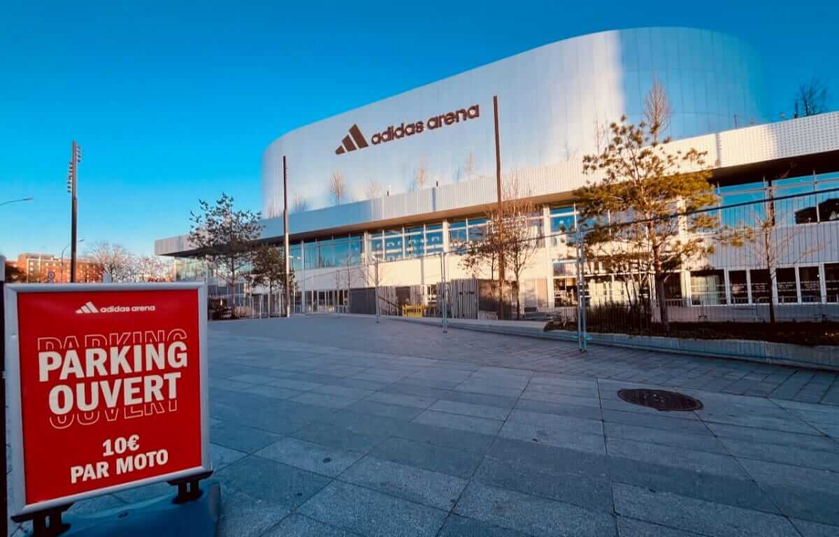 Panneau parking ouvert 10€ par moto devant la façade de l'Adidas Arena Porte de la Chapelle Paris 18