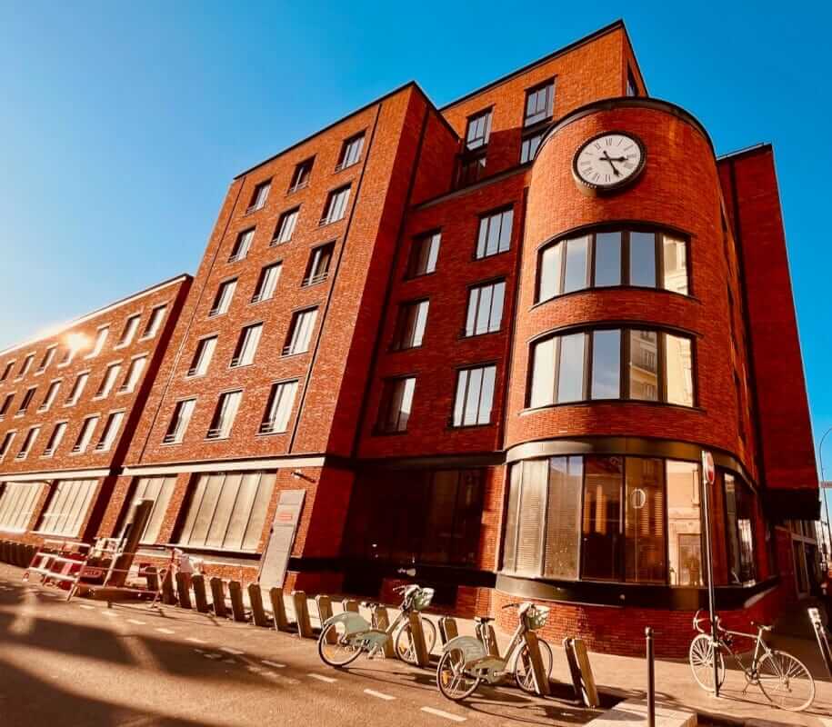 Façade en brique rouge du Mob House Saint-Ouen avec horloge, hôtel design près de Paris