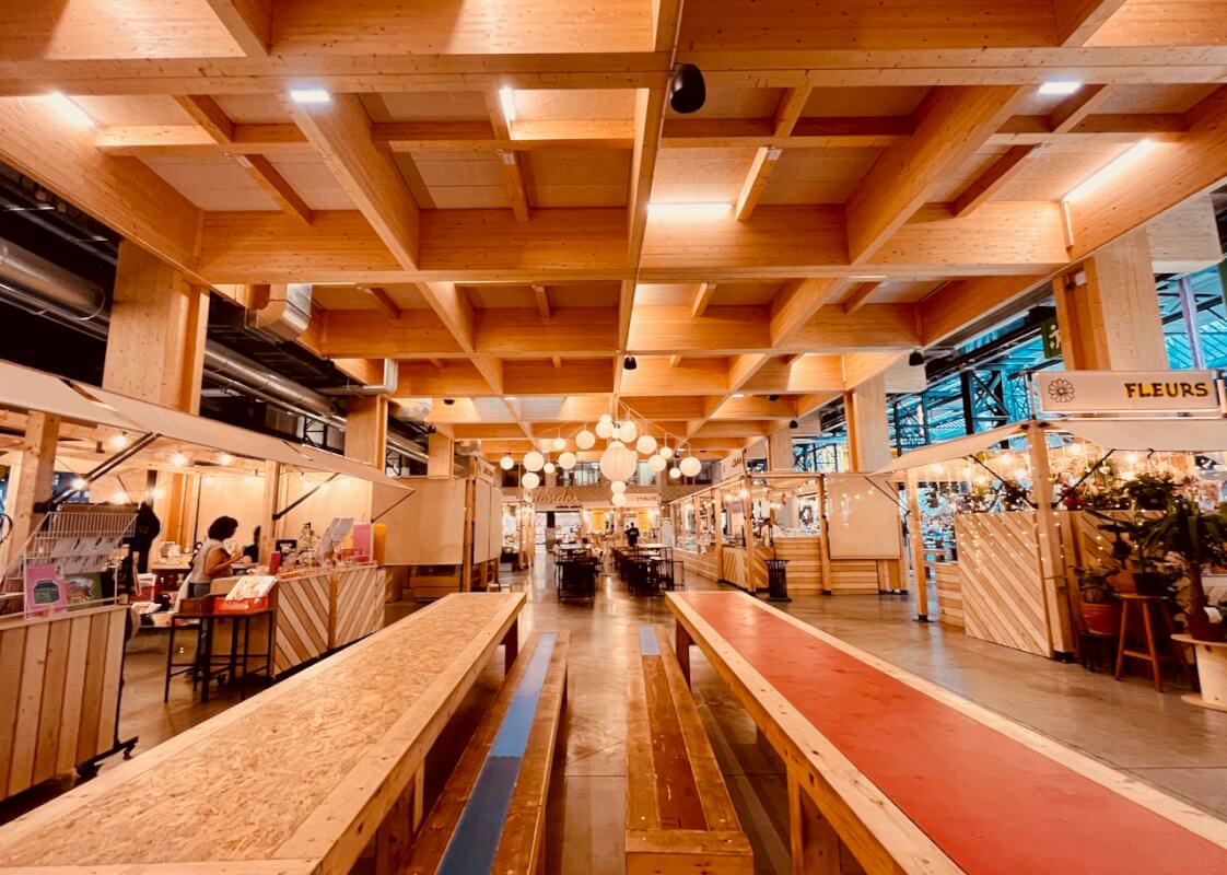 Le marché de la Communale Saint-Ouen — stands alimentaires dont le fleuriste, sous plafond en bois massif
